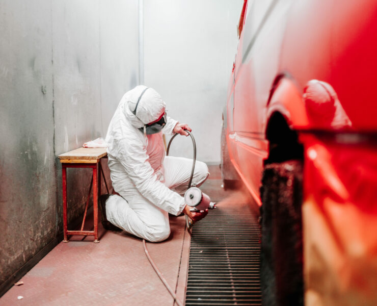 close up details of industrial worker, mechanic engineer painter using a spray brush gun and painting a car