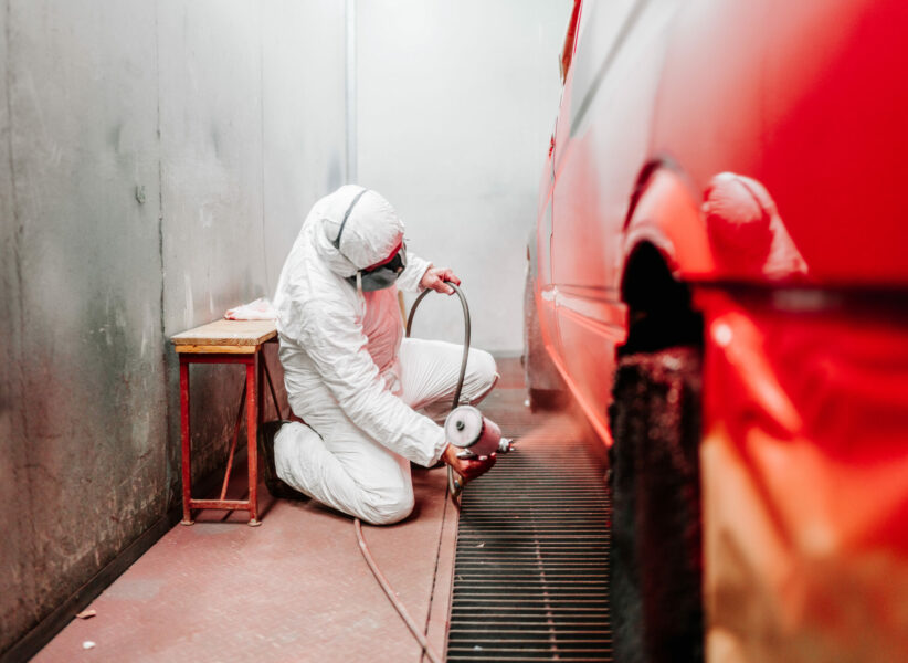 close up details of industrial worker, mechanic engineer painter using a spray brush gun and painting a car