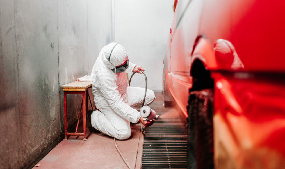 close up details of industrial worker, mechanic engineer painter using a spray brush gun and painting a car